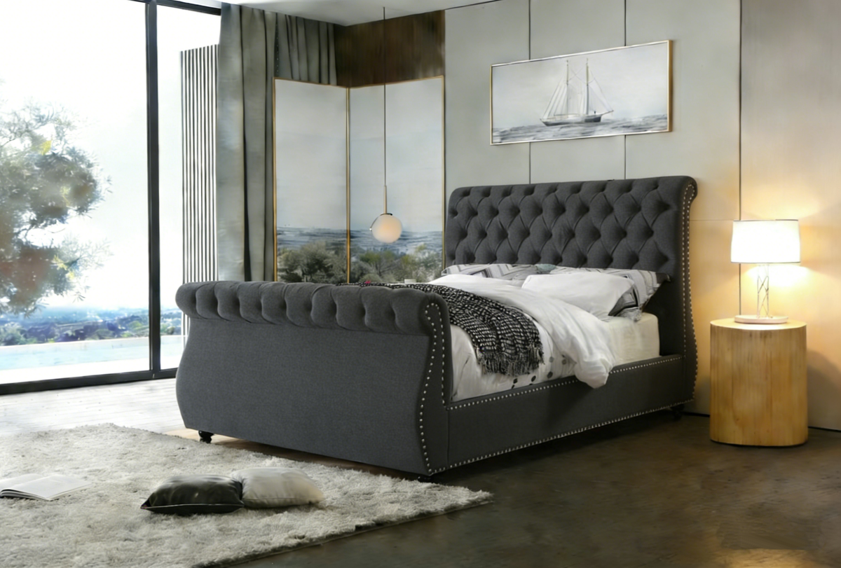 Gray upholstered bed in a modern bedroom with large windows and decorative elements.