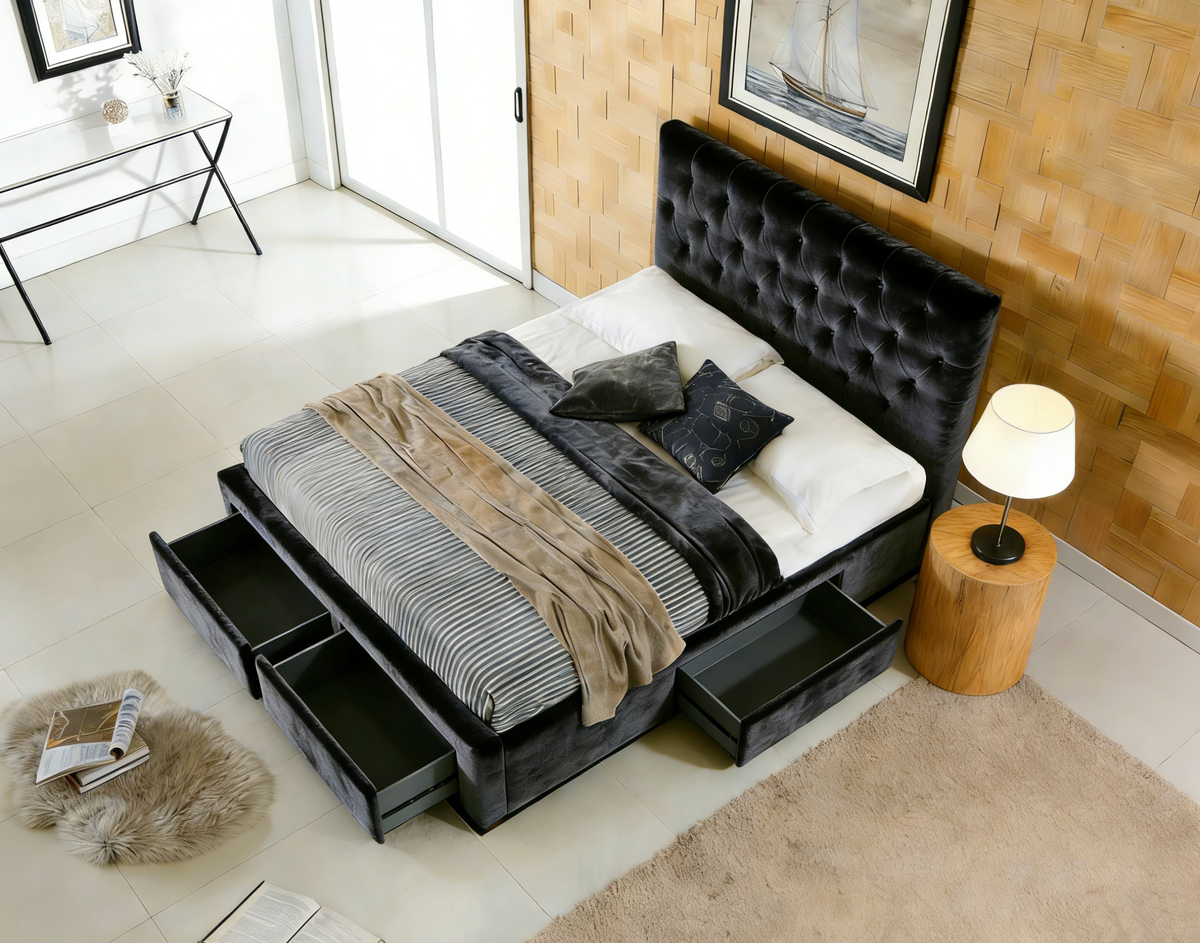 Modern bedroom with a black upholstered bed featuring storage drawers, a lamp, and decor items.