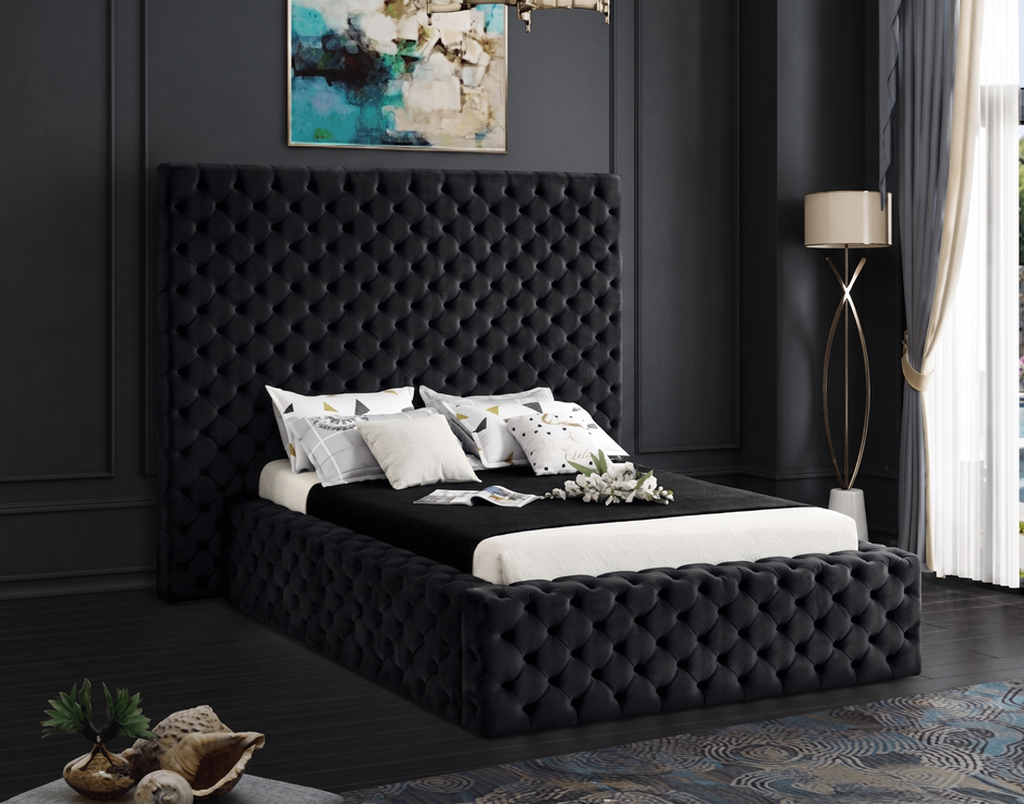 Black tufted bed in a room with dark walls and a window.