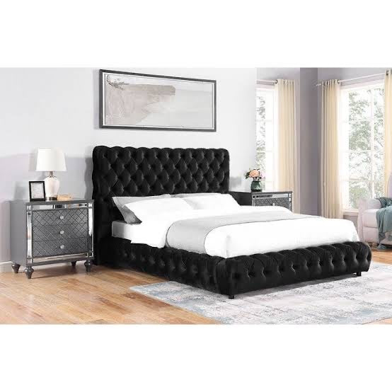 Black tufted bed in a bedroom setting with nightstands and decor.