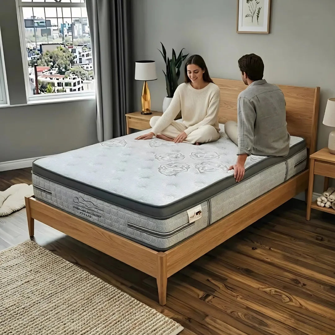 Two people inspecting a mattress in a bedroom setting.